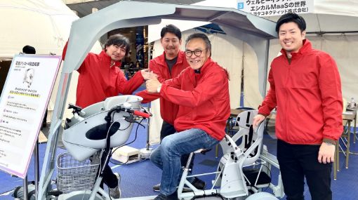 卒業後の取り組みとして屋根付き電動アシスト４輪自転車を開発した笑顔の受講生３名と実機がうつっている