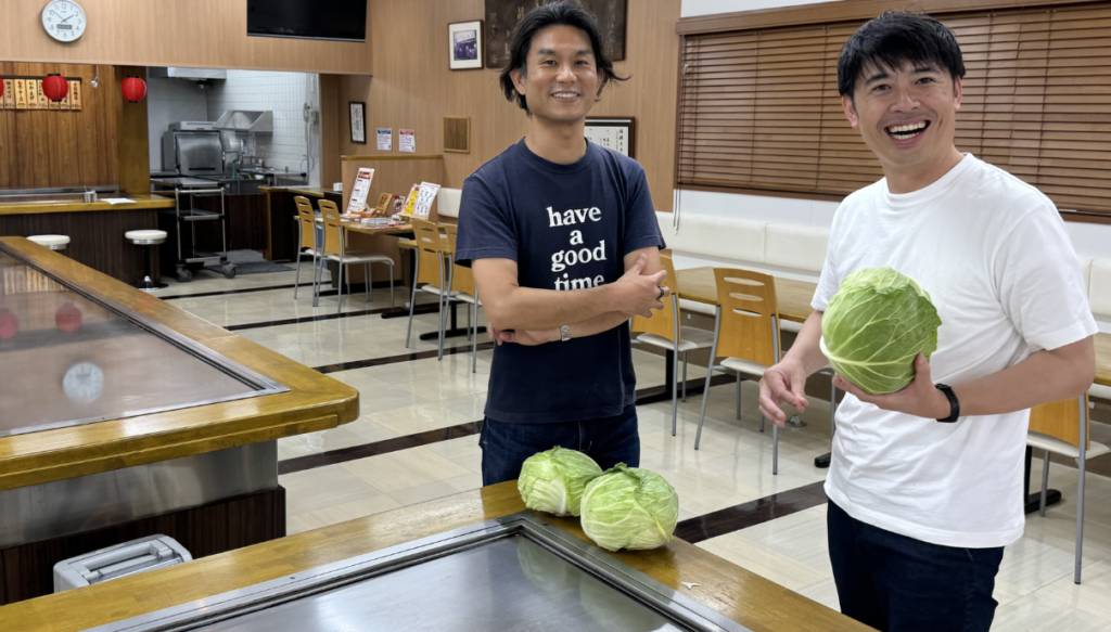 お好み焼き店にて笑顔でキャベツをもつ安永さんと味元さん